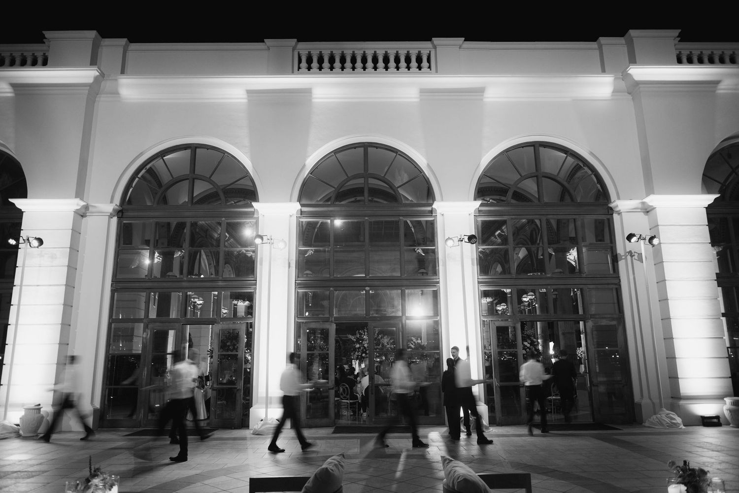 Black and white panorama of an elegant wedding venue entrance with arched windows and columns.