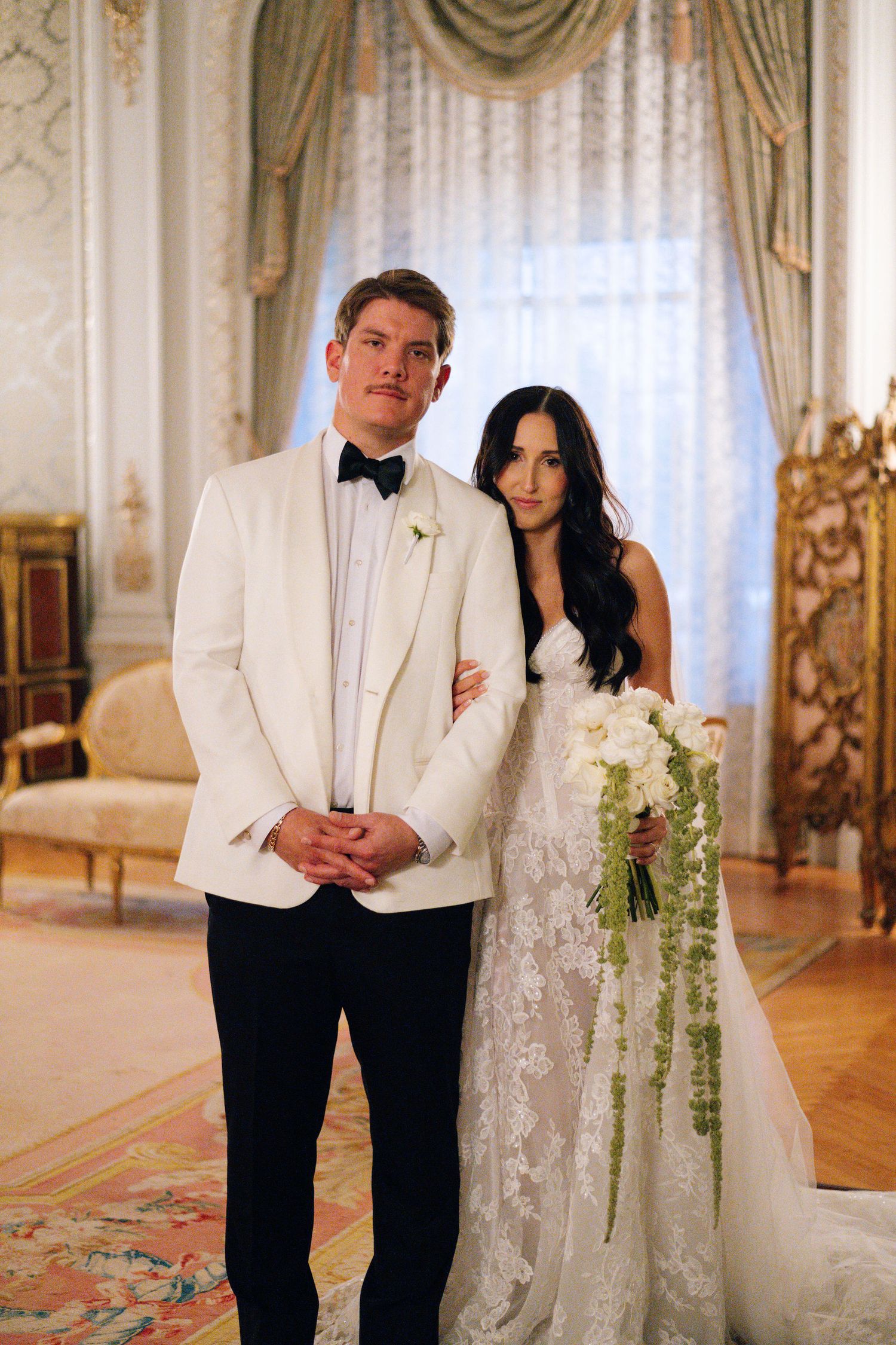 Formal wedding portraits in luxurious interior with elegant drapes and decor.