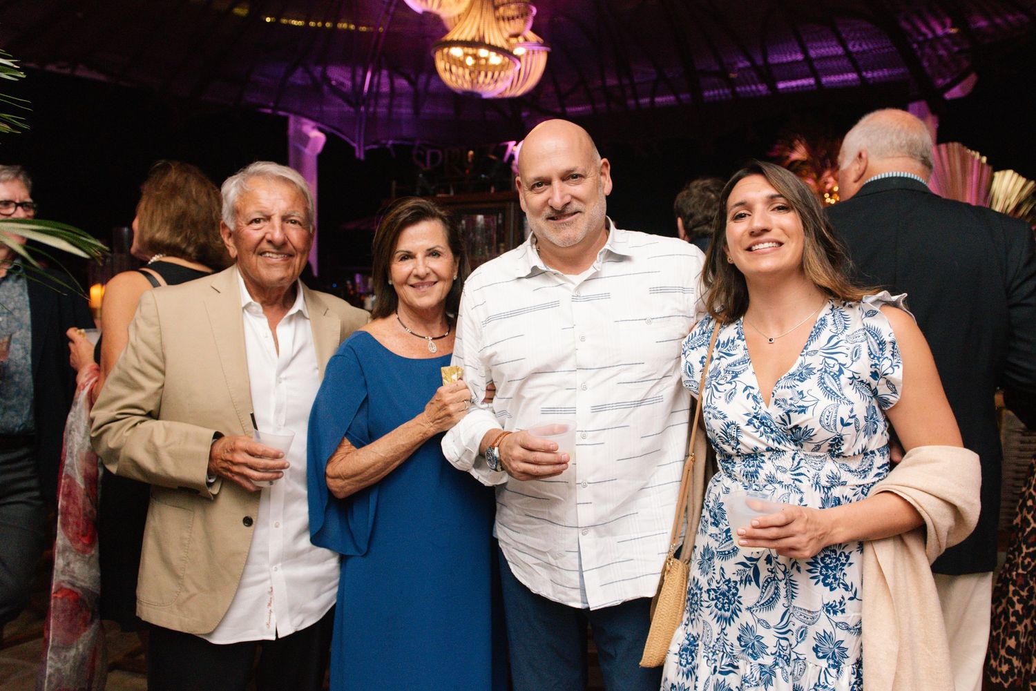 Group of party guests enjoying drinks and conversation at an evening event.
