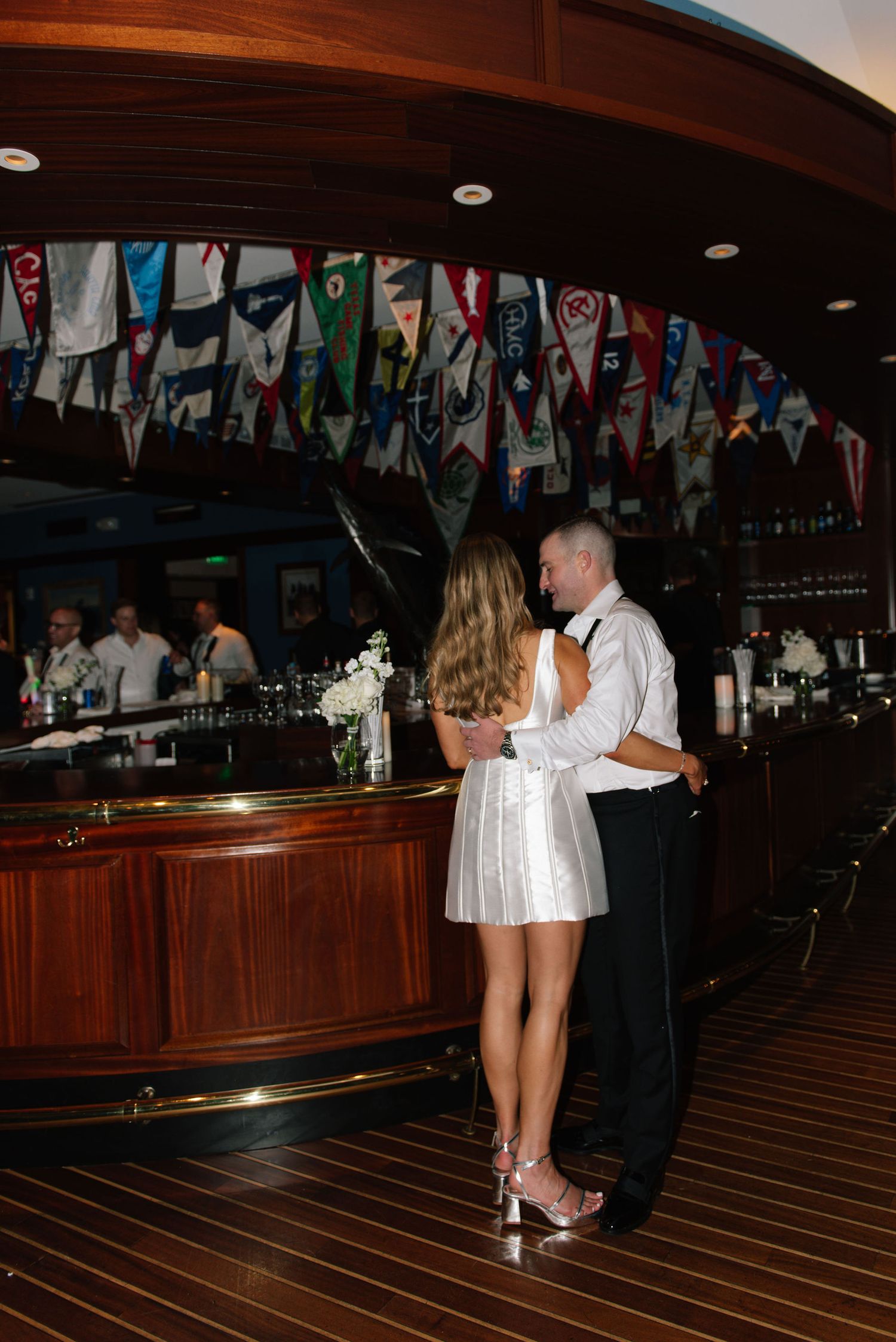 Couple dancing together on a wooden floor under decorative pennant flags at an indoor venue.