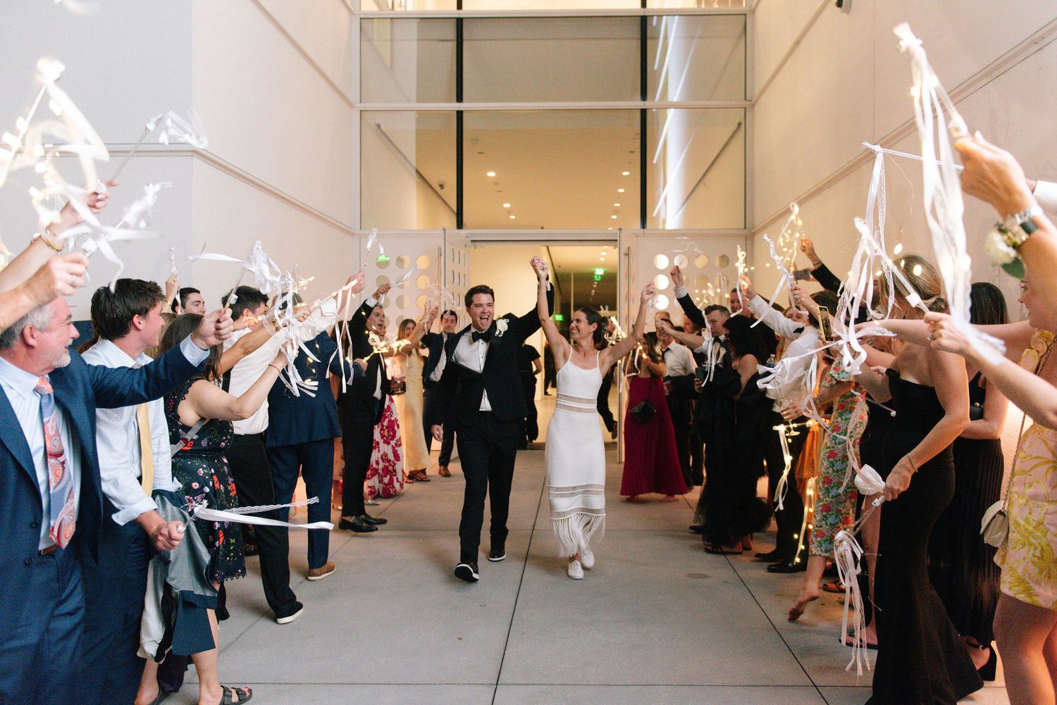 Wedding guests line a hallway waving sparklers as newlyweds make their grand exit.