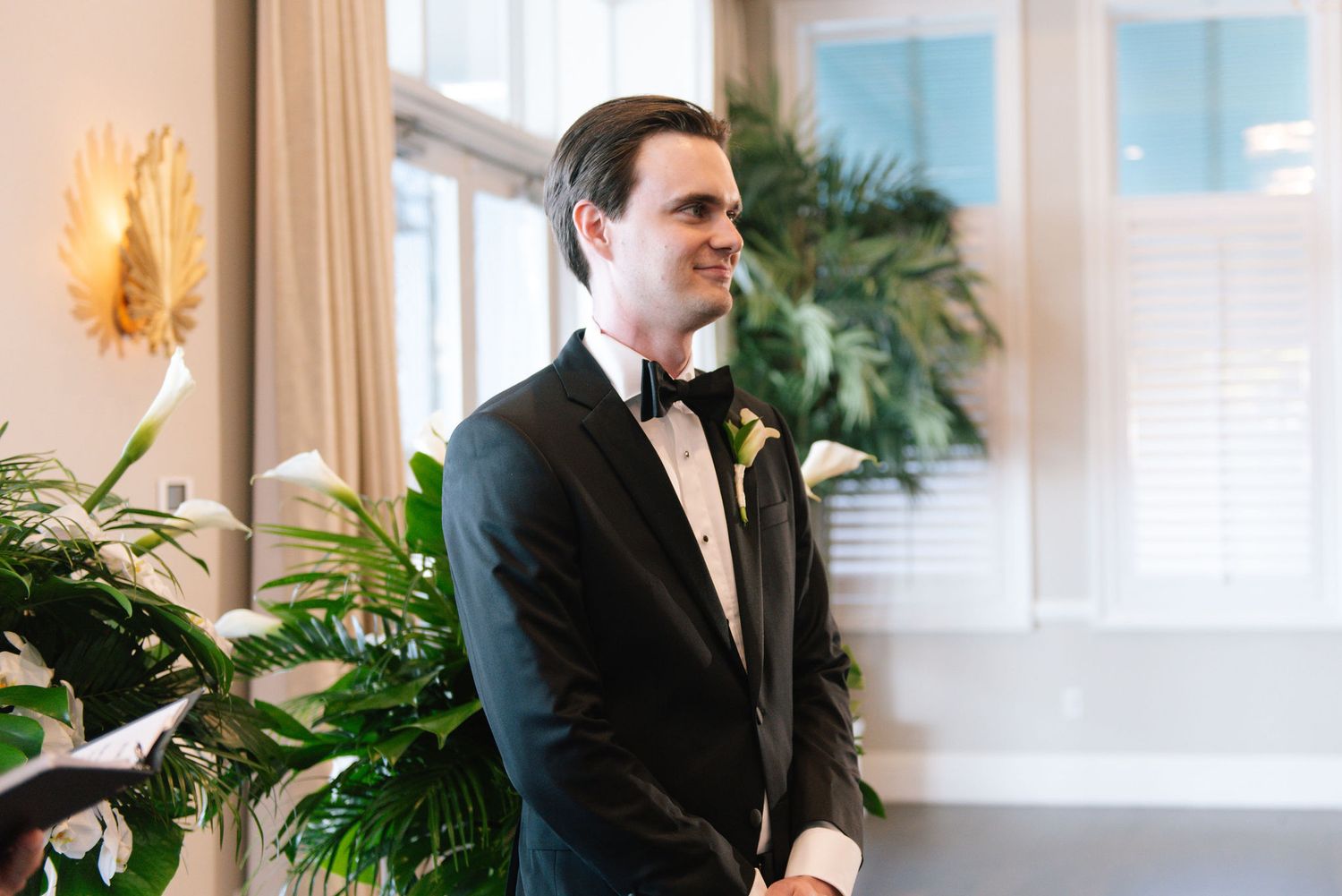 Elegant wedding venue interior with tropical decor and large windows.
