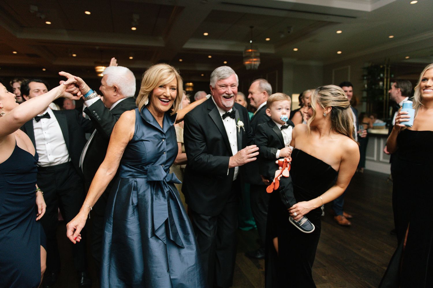 Wedding guests dancing and celebrating on the dance floor at an evening reception.