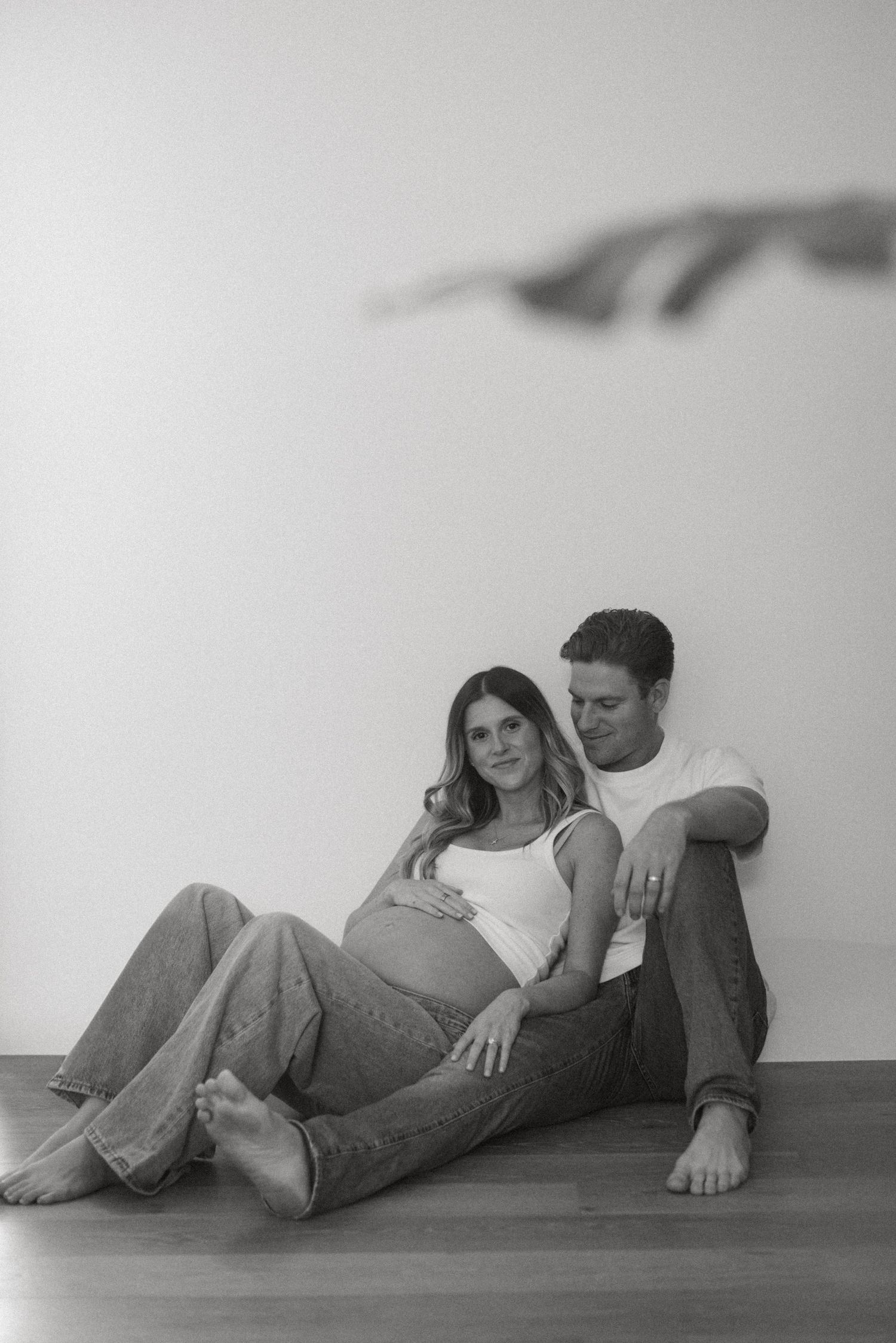 Artistic black and white photo series of a couple lying on a minimalist floor.