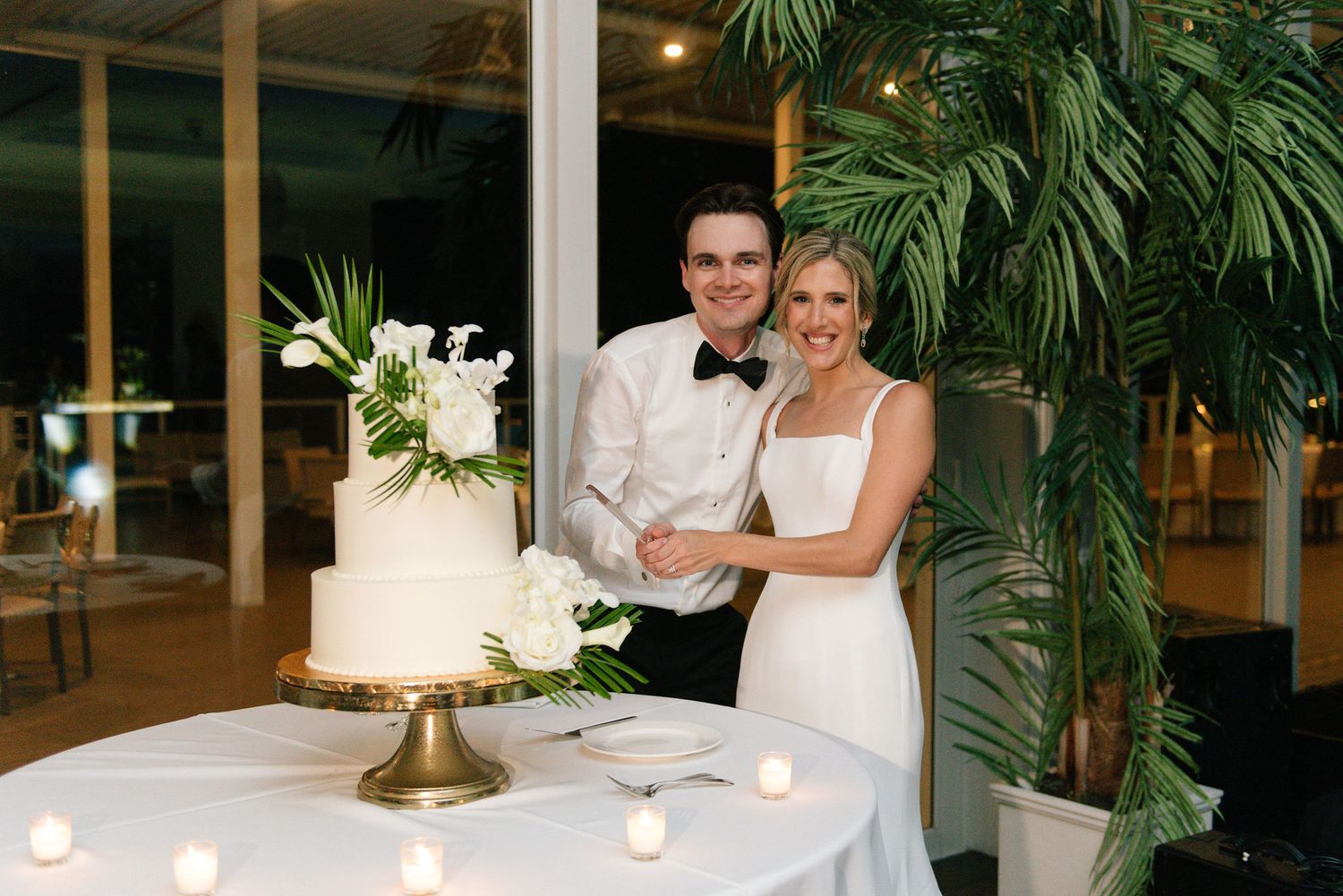 Elegant wedding reception space with tropical decor and candlelit ambiance.