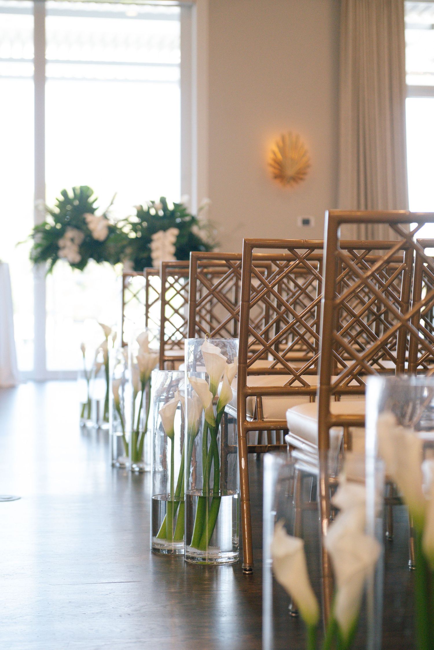 Modern wedding ceremony space with wooden chairs and white floral arrangements.