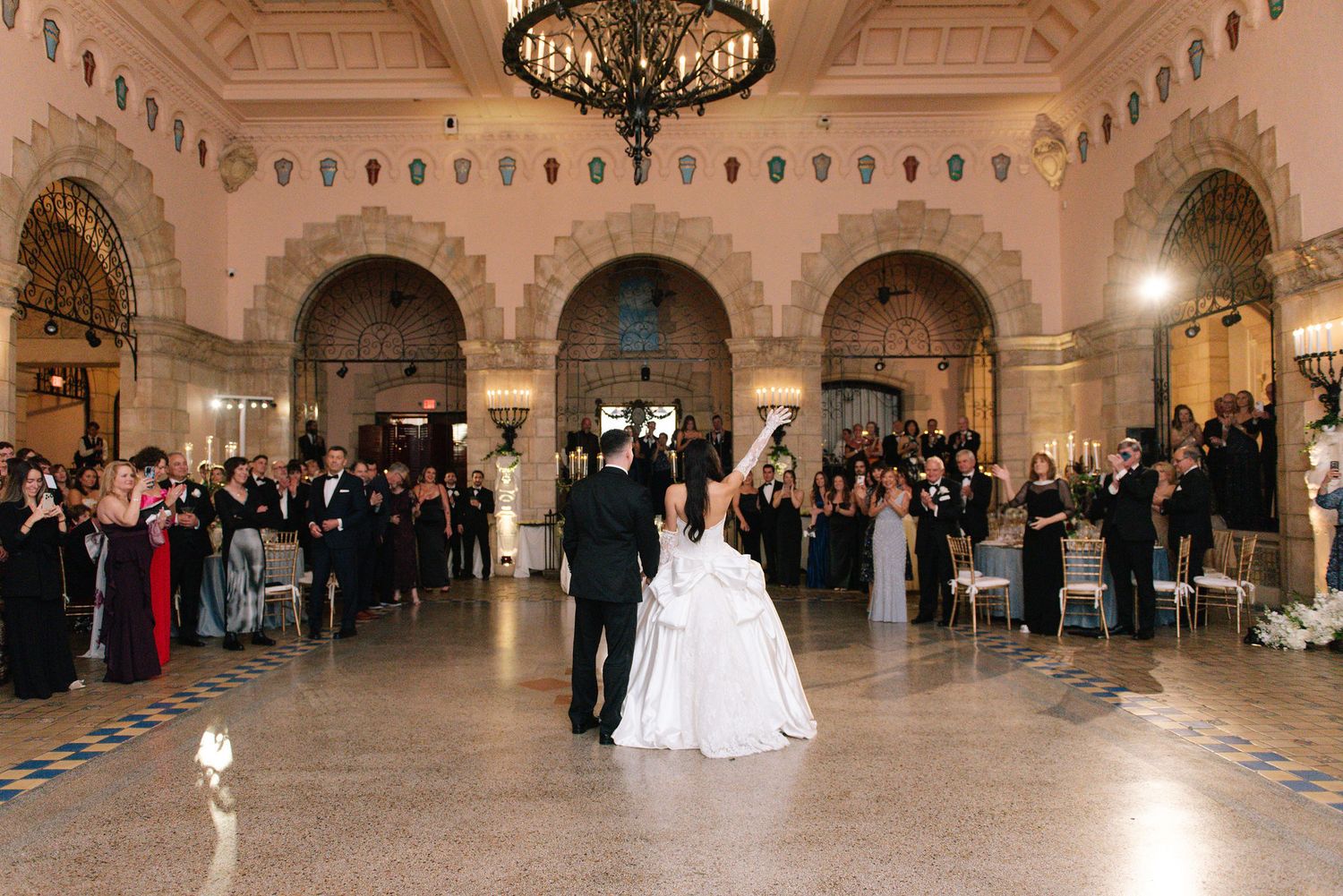 Panoramic view of an elegant ballroom with ornate architecture, chandeliers, and guests gathered for a formal event.