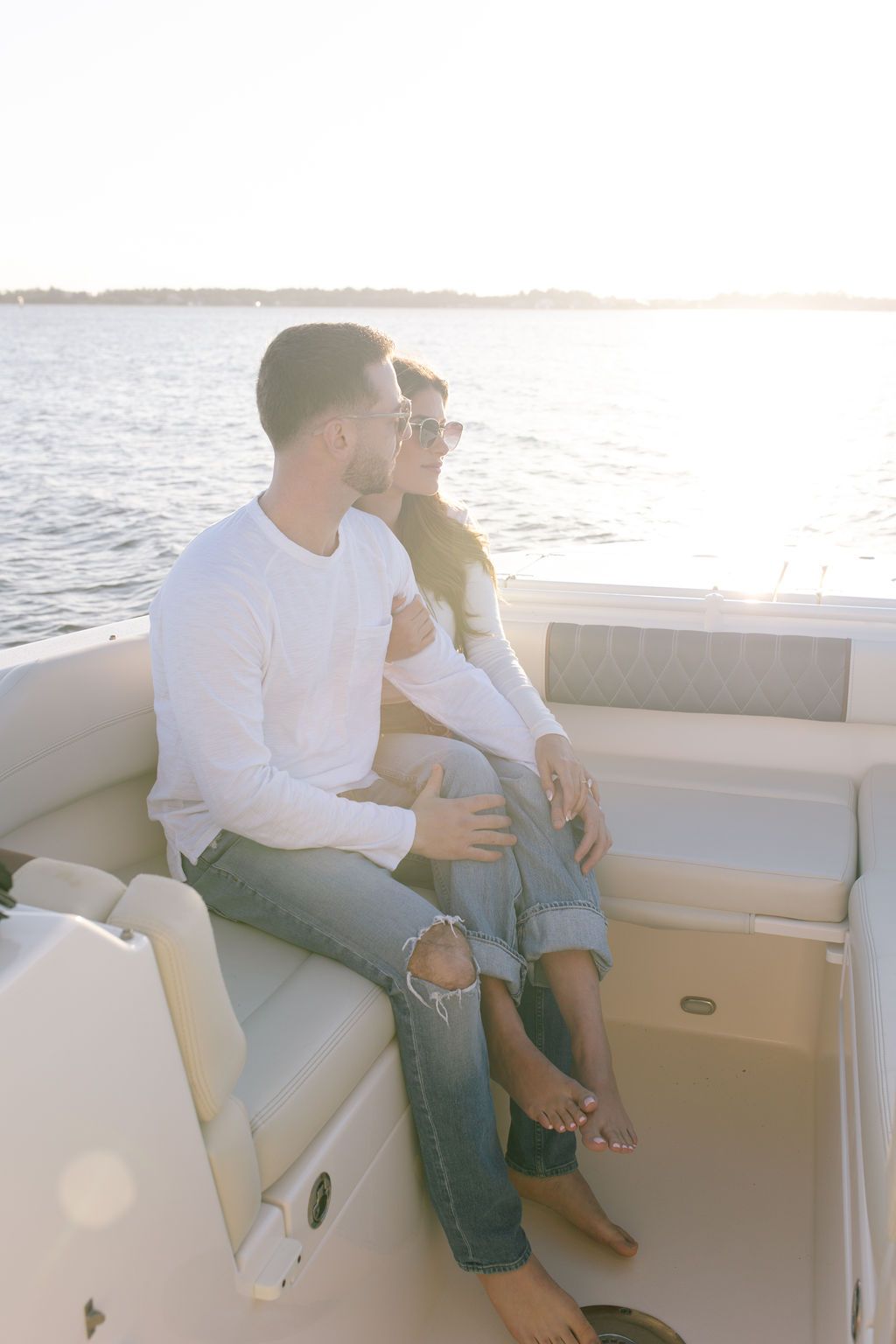 Romantic couple relaxing on white boat seats during golden hour on the water.