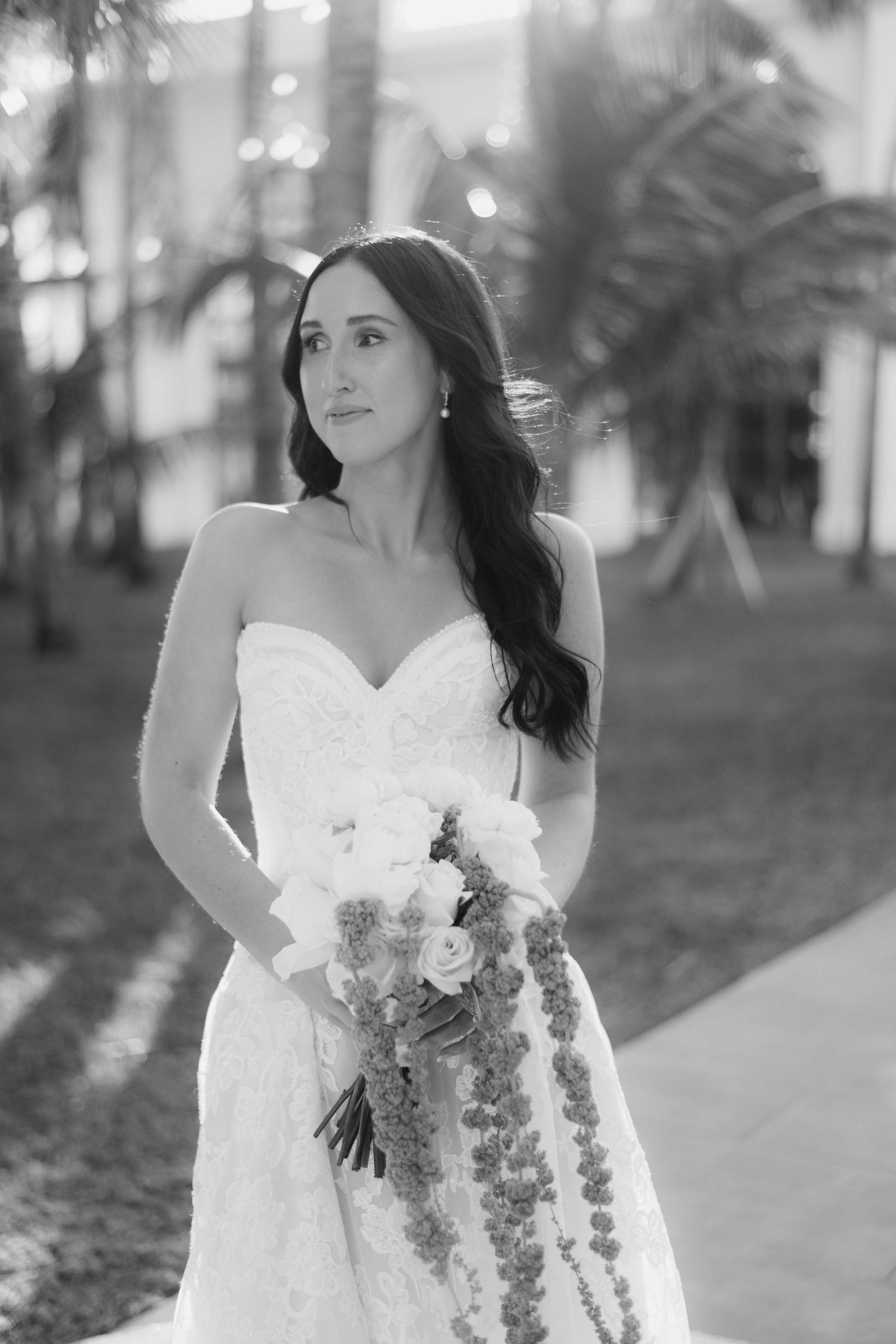Black and white bridal portraits with cascading bouquet against architectural backdrop.