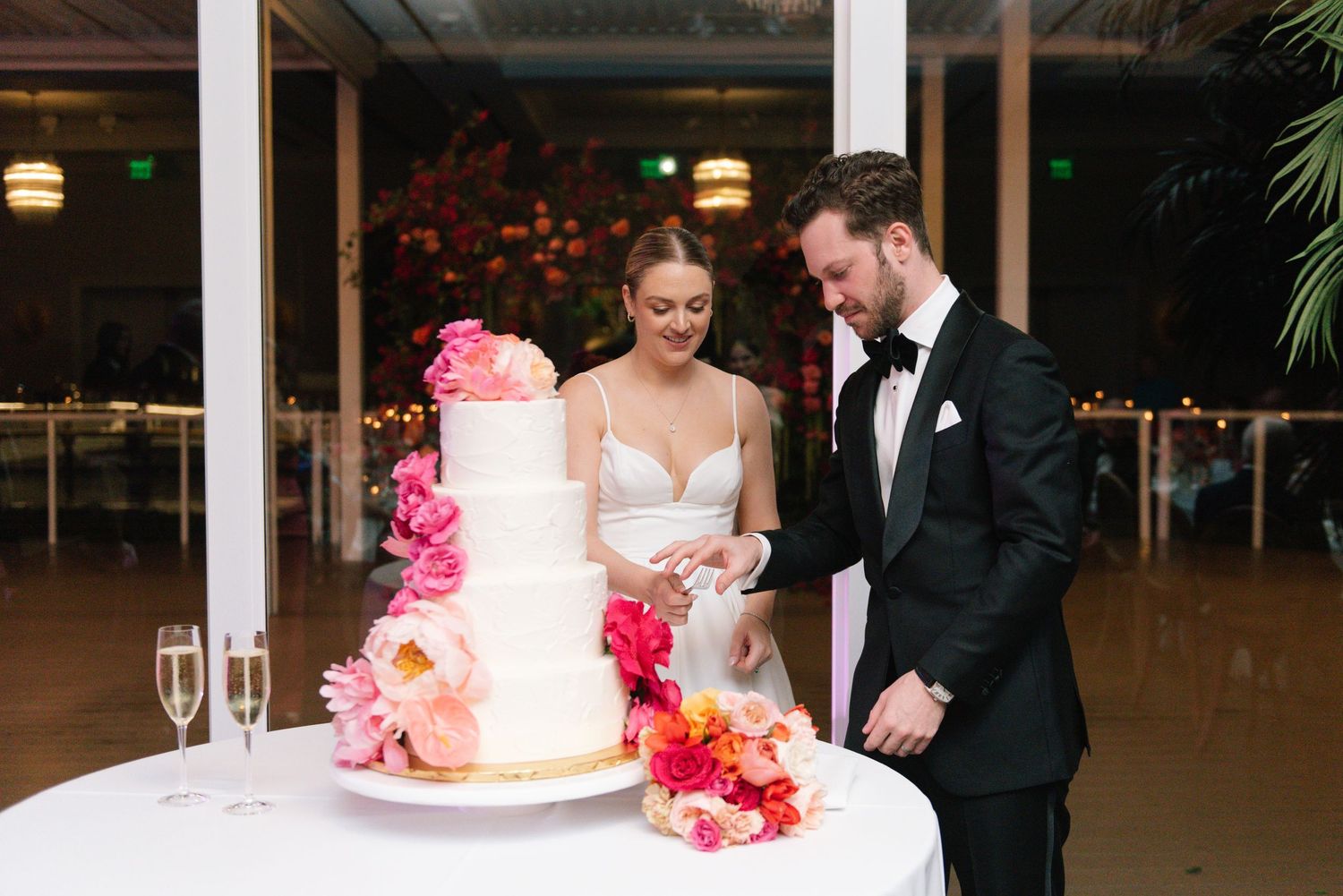 Wedding celebration with elegant table settings and pink floral arrangements at an indoor venue.