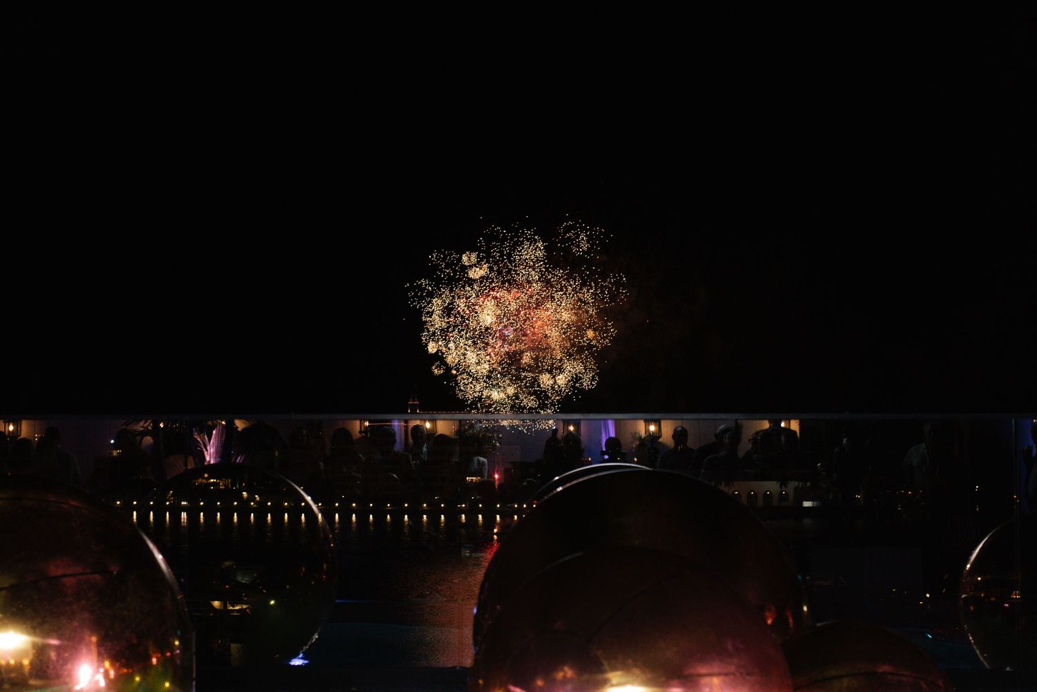 Colorful fireworks display illuminating a dark night sky over water.