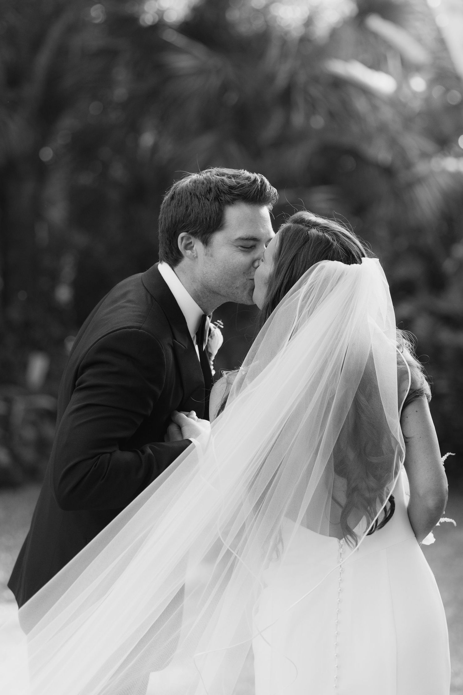 Black and white romantic wedding moment captured in an intimate outdoor setting.