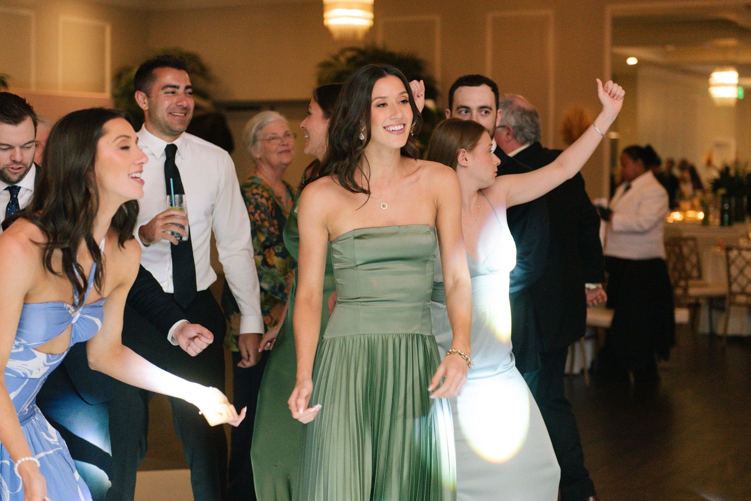 Wedding guests dance and celebrate on a checkered dance floor at an elegant reception venue.