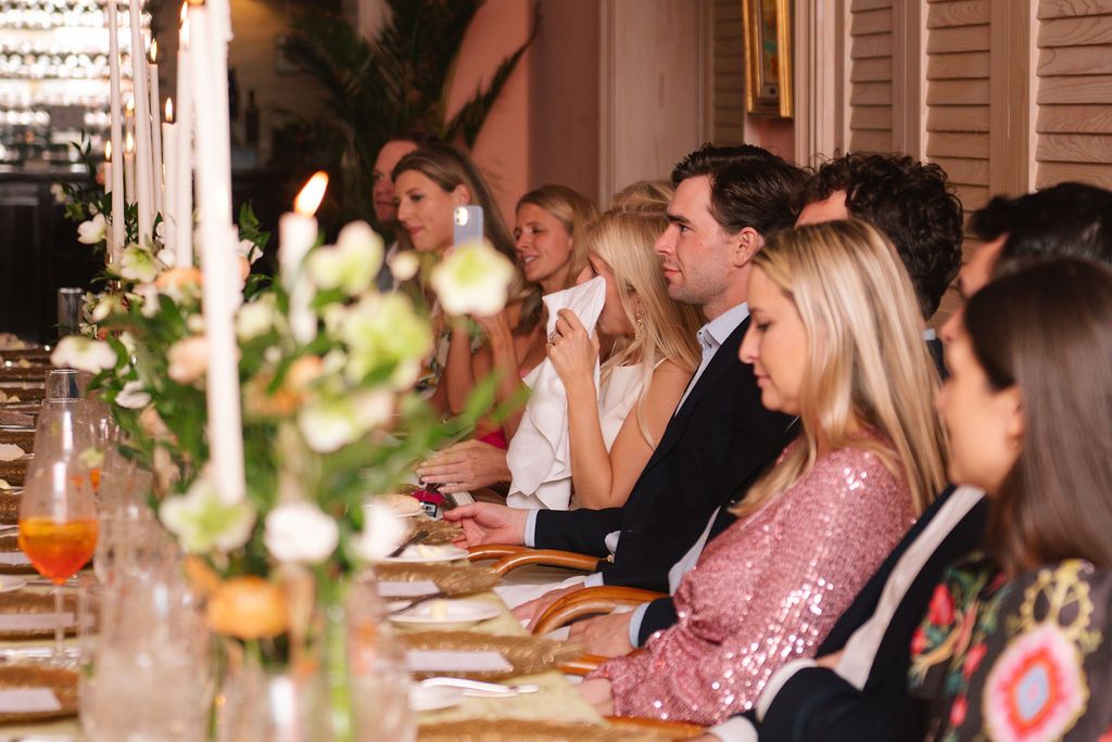 Elegant dinner party with candlelit table settings and floral centerpieces.