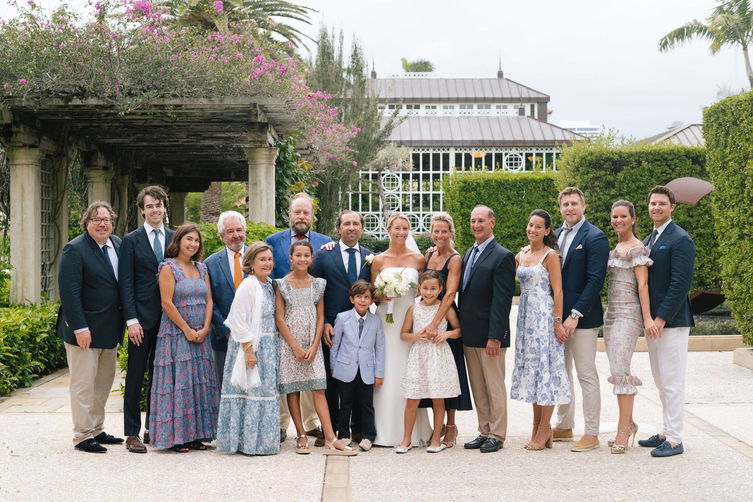 Wedding party and guests assembled on stone pathway surrounded by lush tropical landscaping.