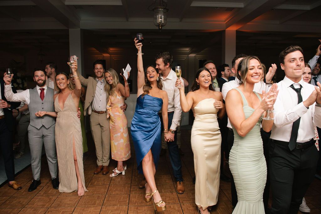 Wedding guests dance and celebrate on a crowded reception dance floor.