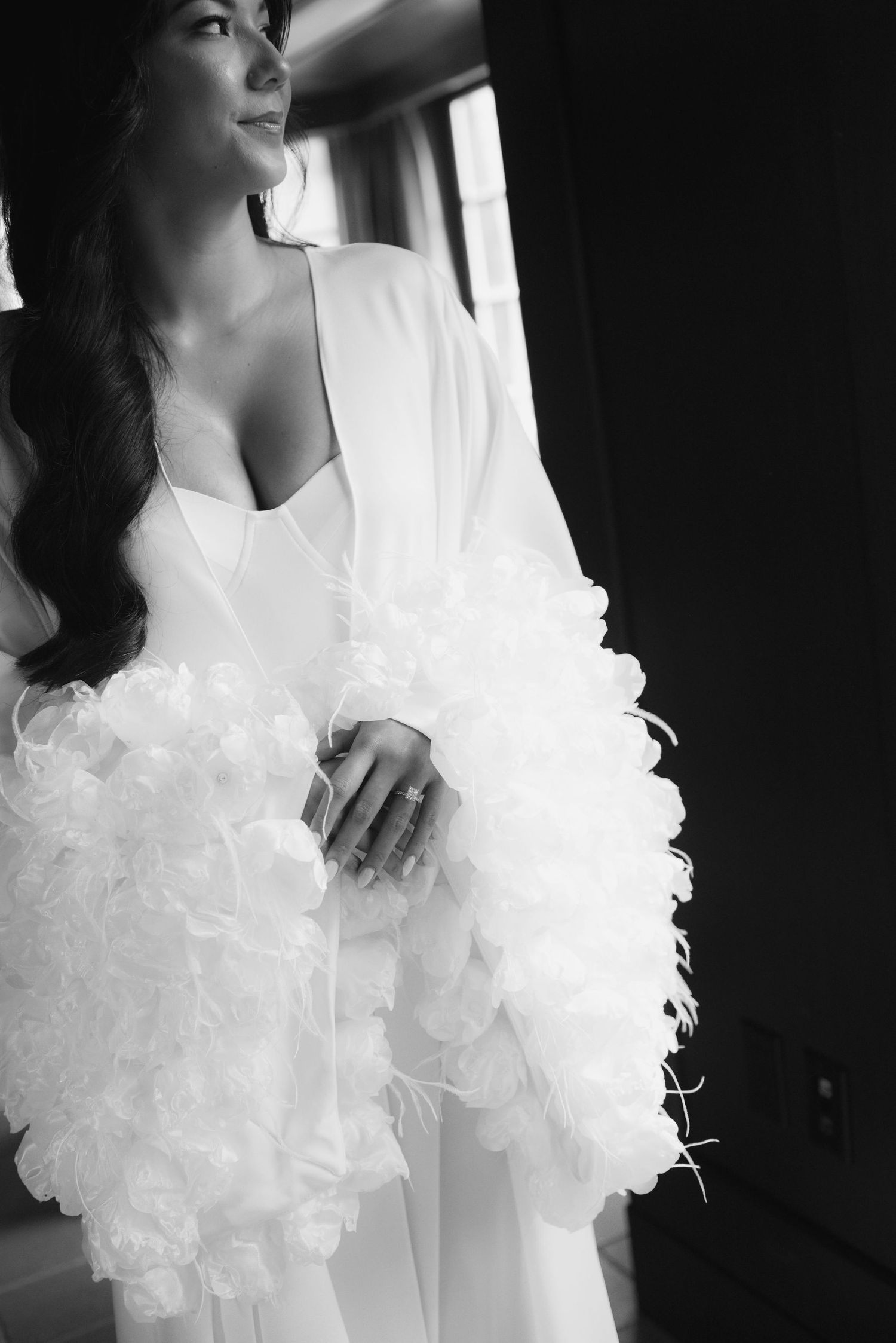 Artistic black and white portrait showing feathered sleeve details of a white robe.