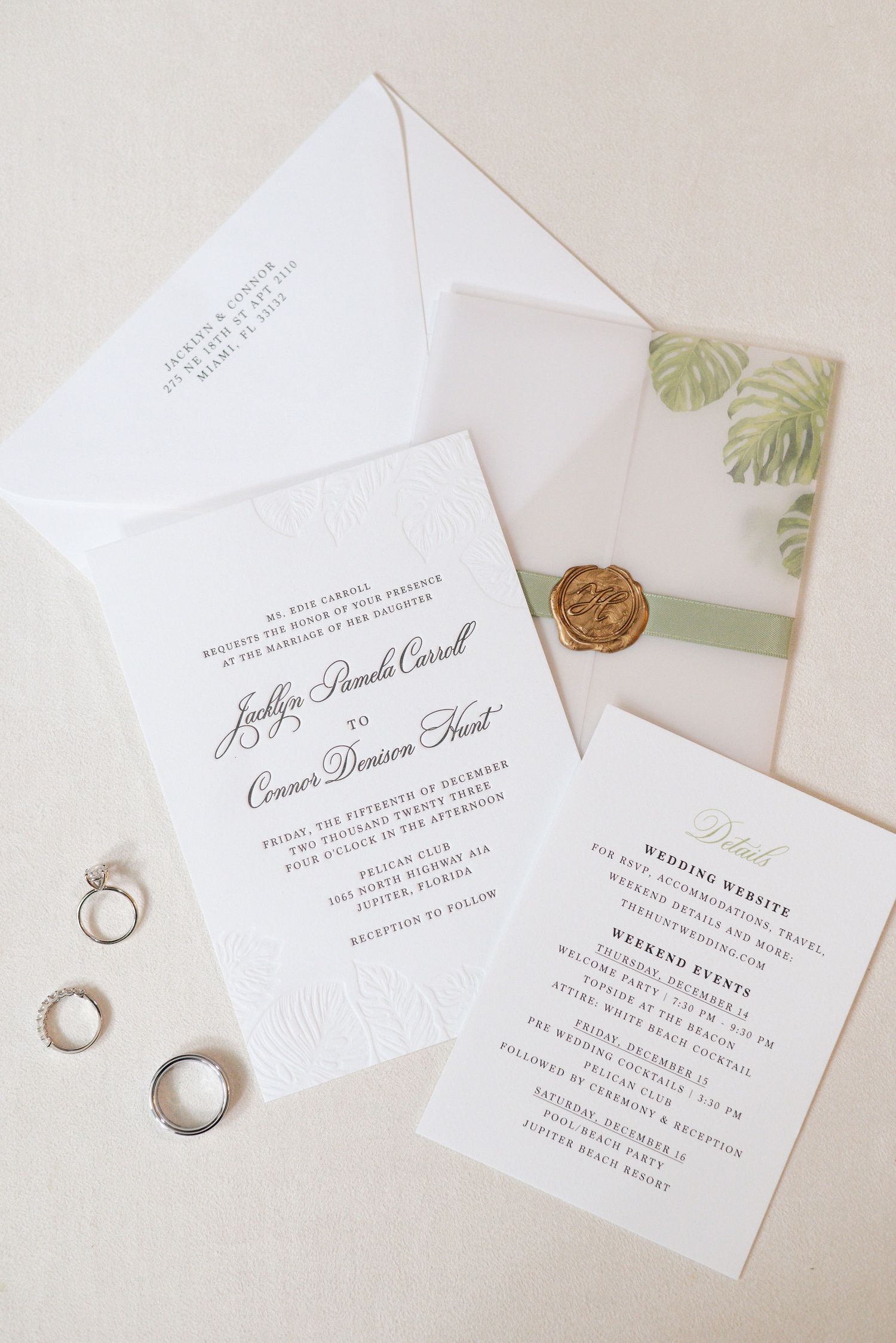Minimalist wedding invitations with tropical leaf details and wedding rings on white background.