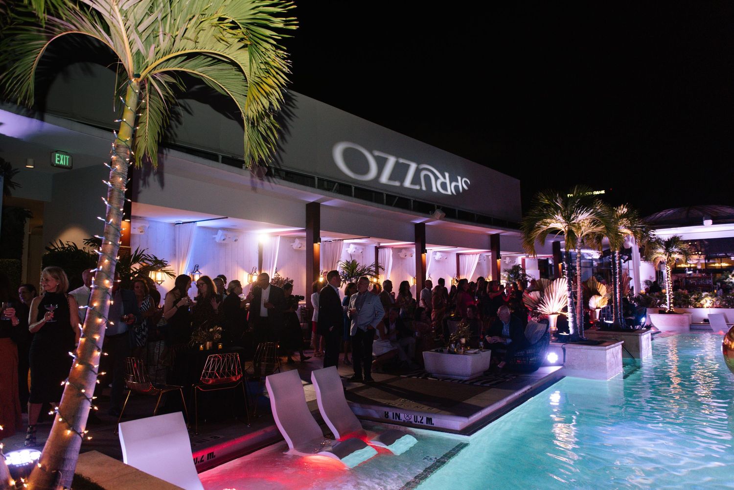 Nighttime pool party with colorful lighting and guests enjoying the outdoor venue.