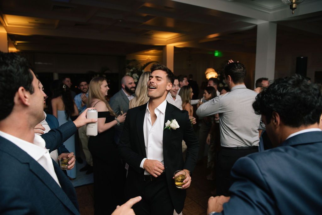 Wedding guests laugh and celebrate on the dance floor during the reception.