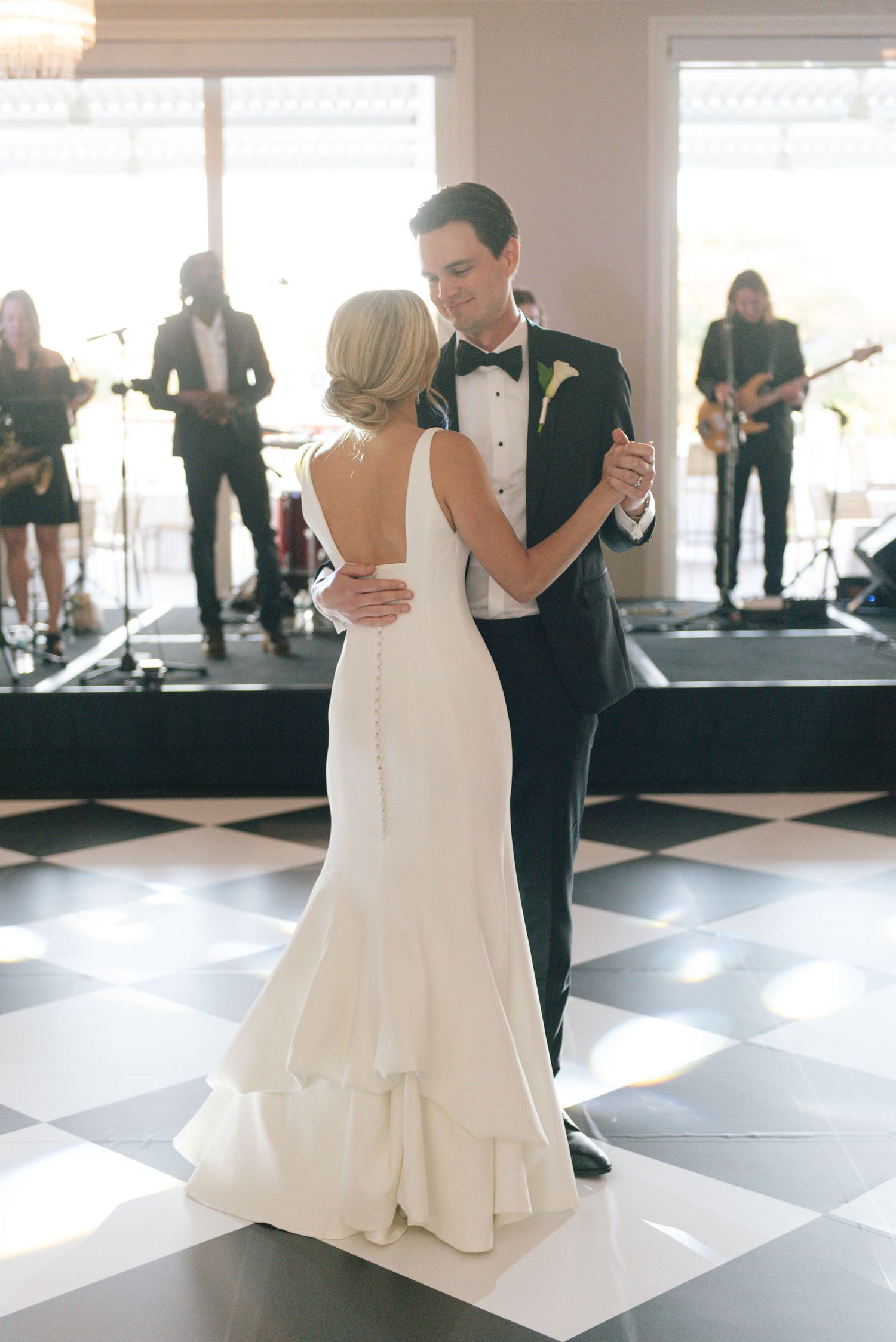 Couple shares their first dance on a black and white checkered dance floor.