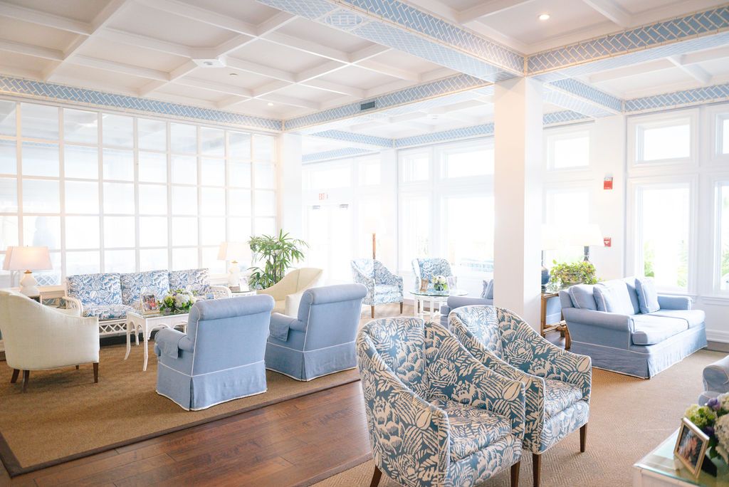 Elegant coastal-style lounge area with blue and white decor, comfortable seating, and natural lighting.