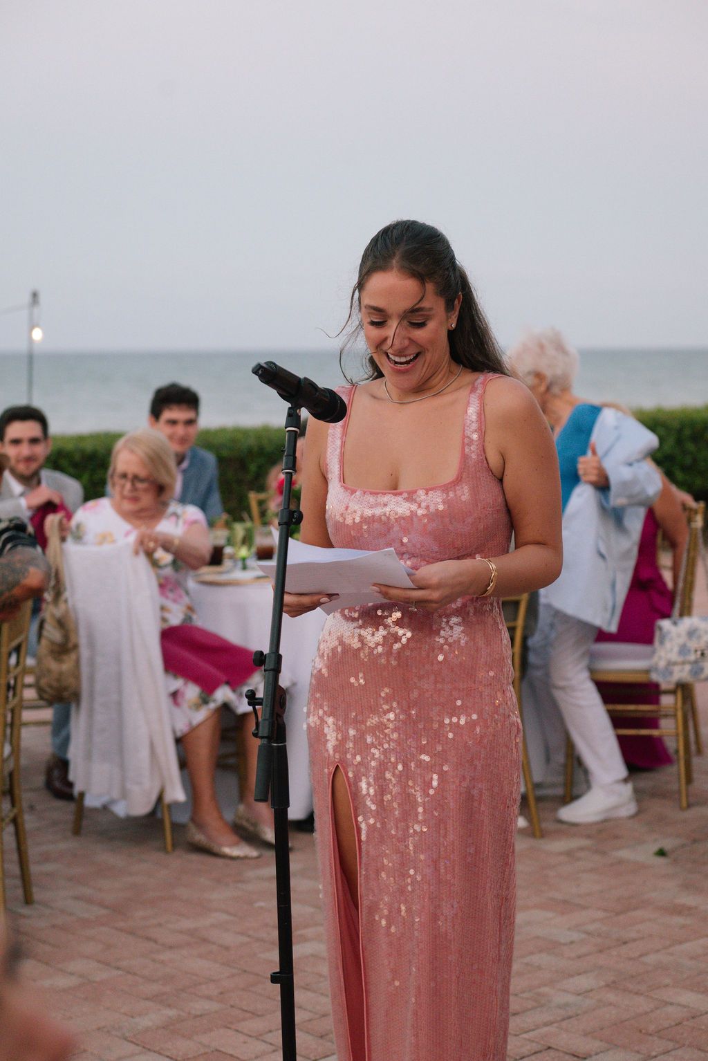 Wedding speech being delivered at an outdoor reception by the ocean.