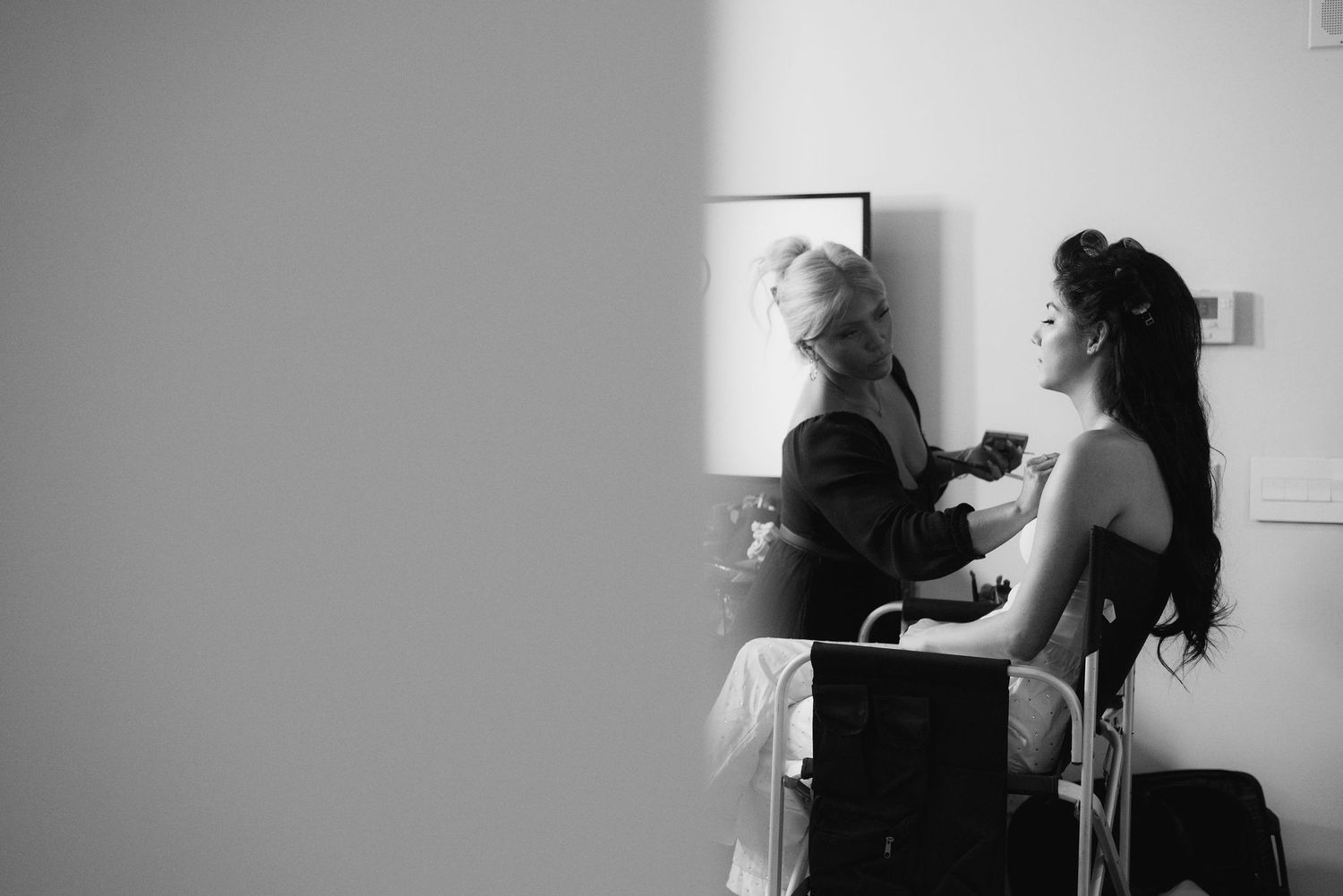 Black and white photograph of wedding preparation moment in natural light.