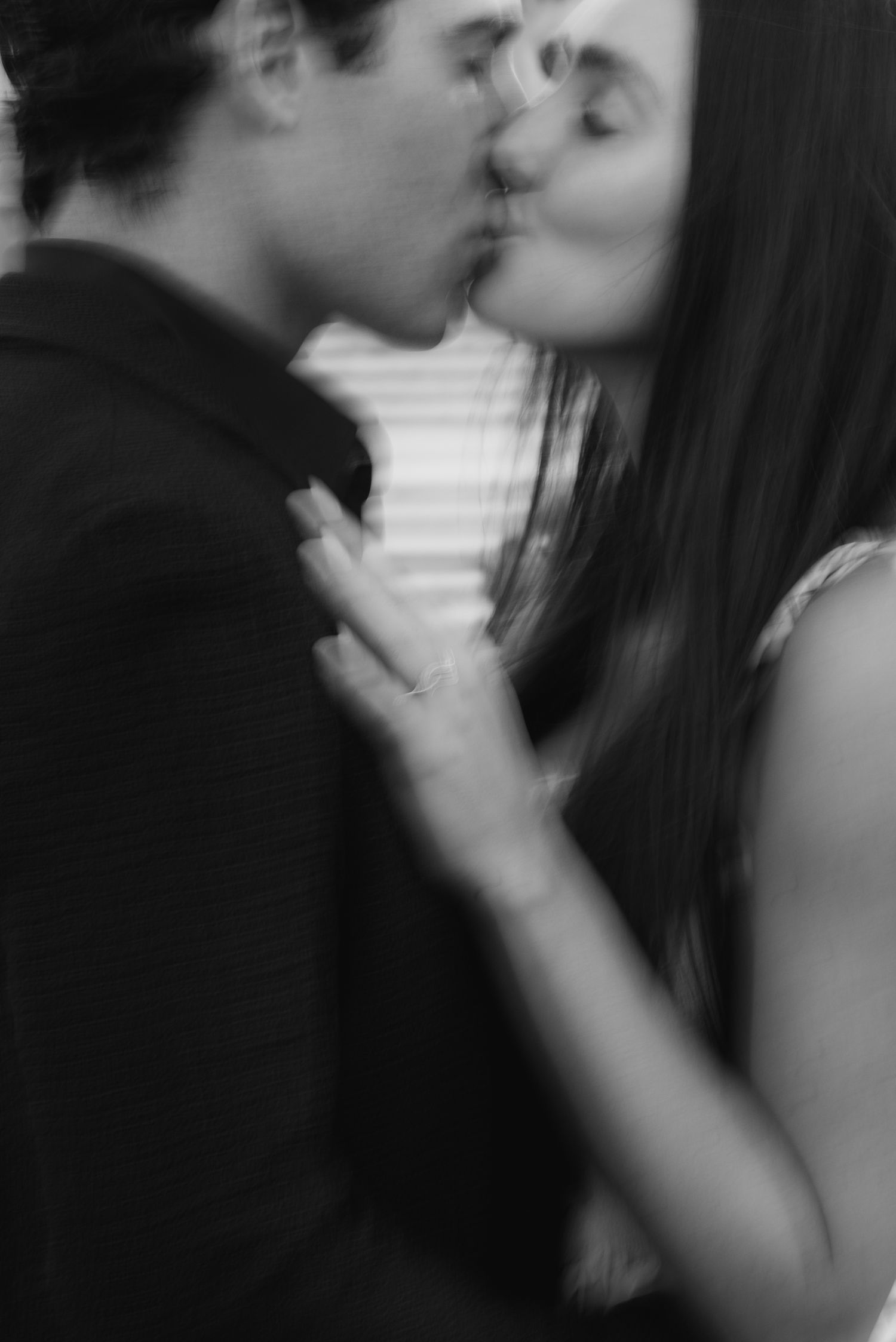 A romantic black and white photo shows a couple sharing an intimate kiss in soft focus.