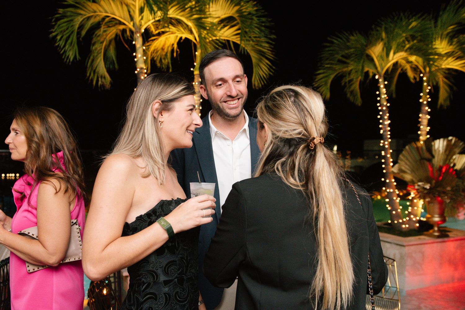 A nighttime celebration with illuminated palm trees creating a festive atmosphere.