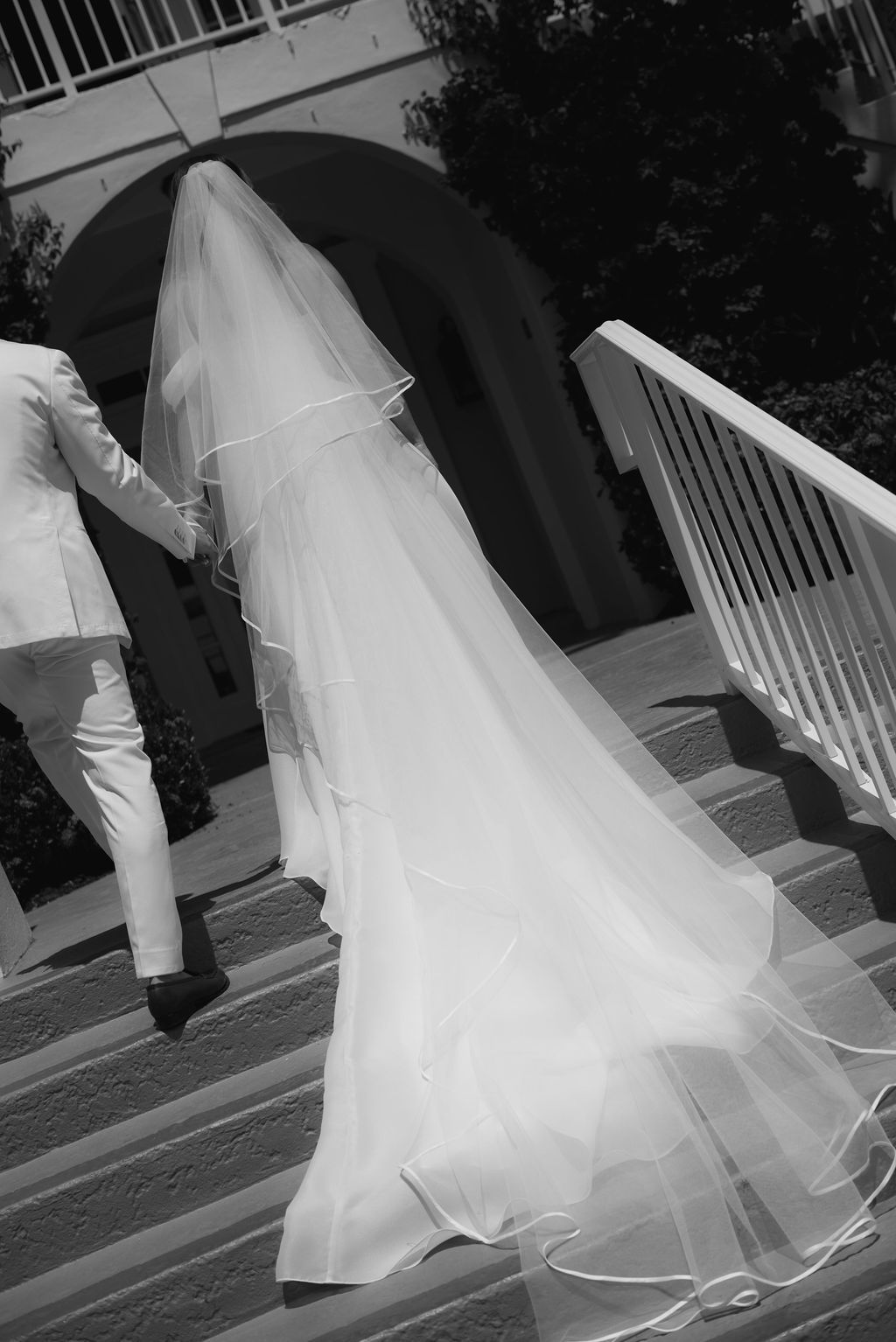 Ethereal white wedding dress train captured in black and white on outdoor steps.