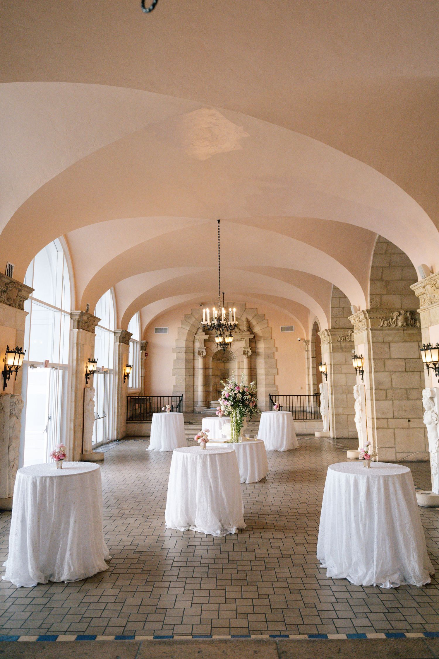 Elegant reception venue with arched ceilings and round tables draped in white linens.