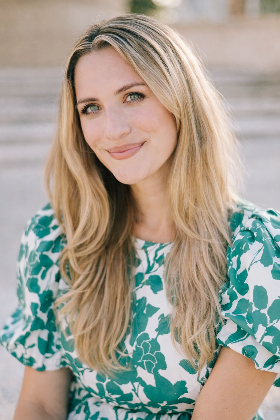 Portrait in a green floral print dress against a beachy background.