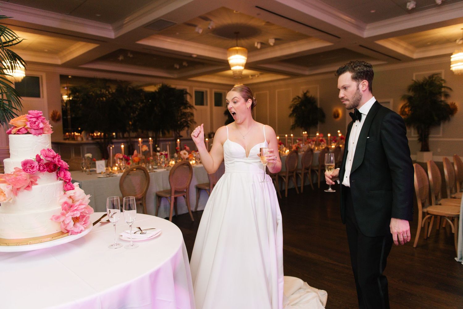 Wedding reception celebration in an elegant ballroom with coffered ceilings and warm lighting.