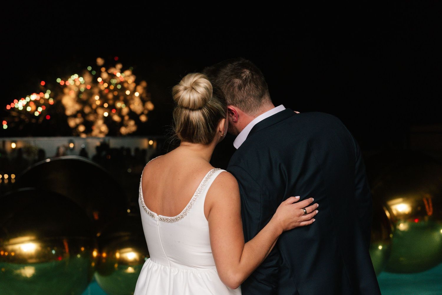 Couple enjoying romantic moment at nighttime poolside celebration.