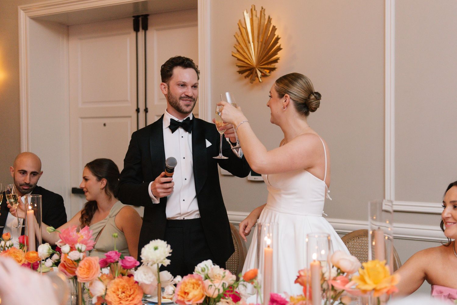 Wedding reception dinner table decorated with gold accents and tropical palm leaf decor.