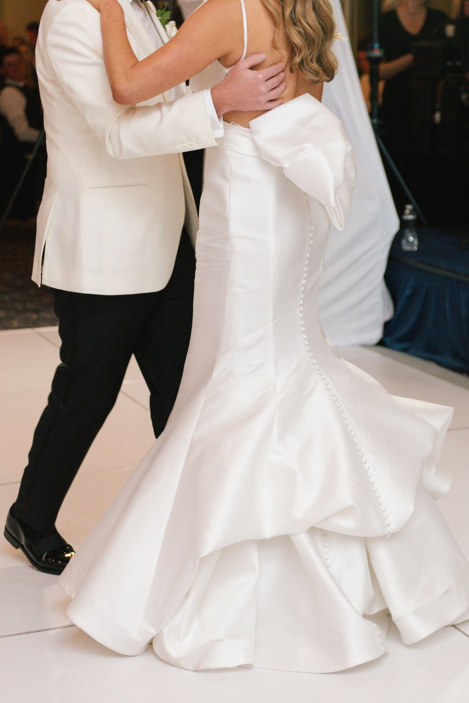 Couples dancing in formal attire on a white dance floor at an elegant wedding reception.