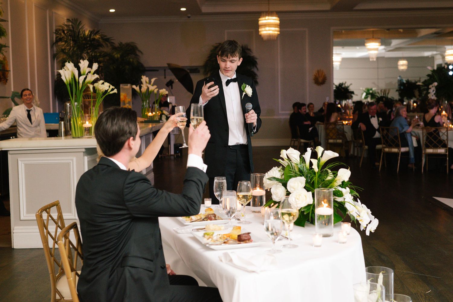 Elegant wedding reception venue with white floral centerpieces and ambient lighting.