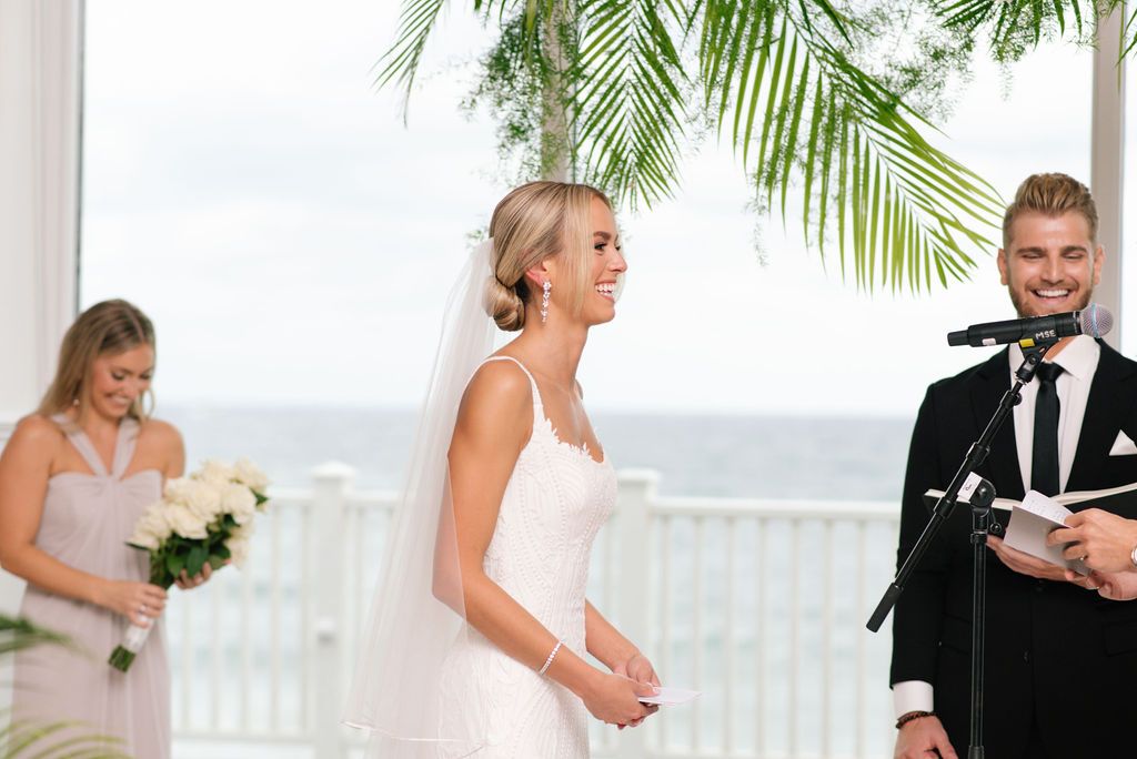 Seaside wedding ceremony with tropical palm decor and ocean view in background.