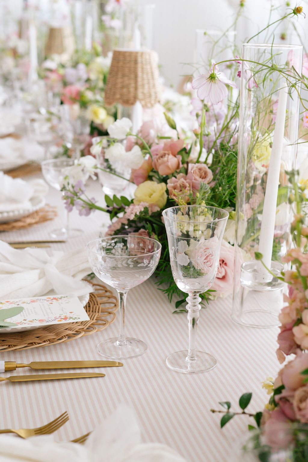 Wedding reception table with pink floral centerpieces and crystal glassware.