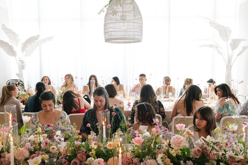 Overhead view of an elegant brunch table setting with pink floral arrangements and glassware.