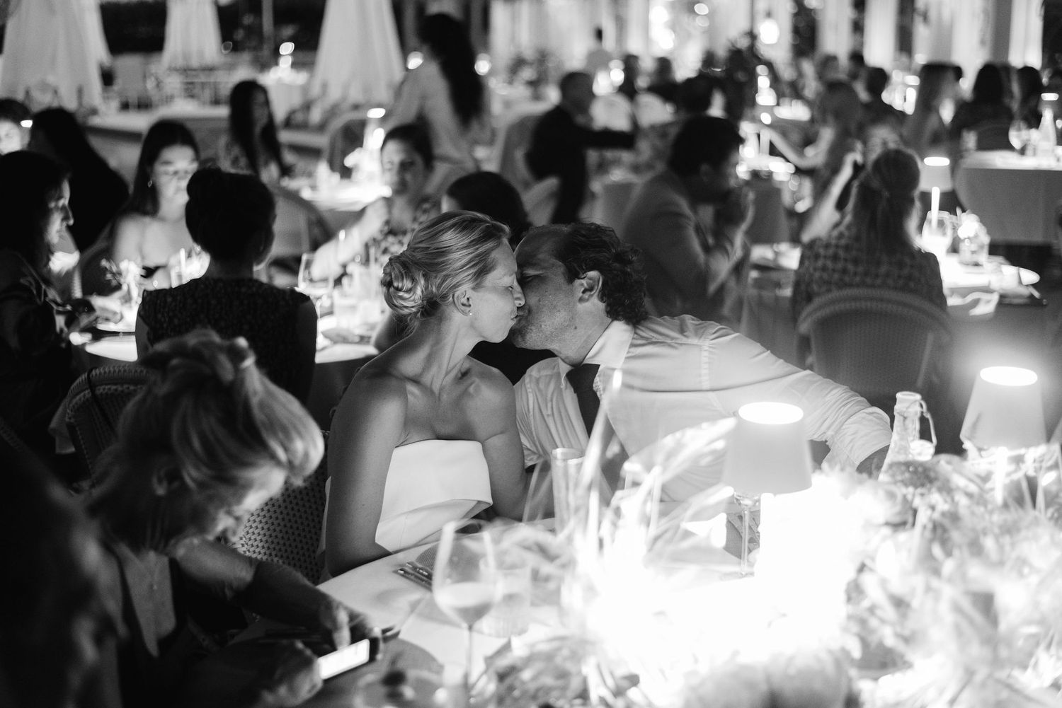 Candlelit wedding reception with guests seated at elegant tables under greenery.