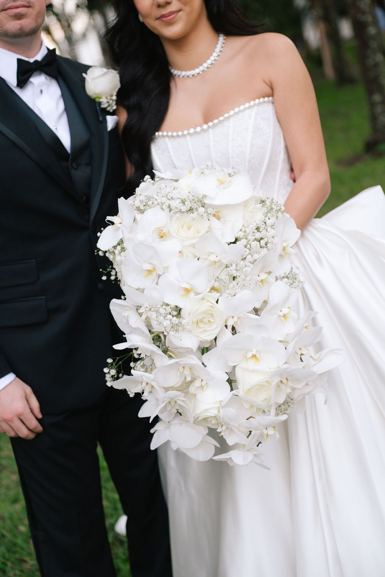 Close-up of a stunning white orchid and rose bridal bouquet with pearl accents.