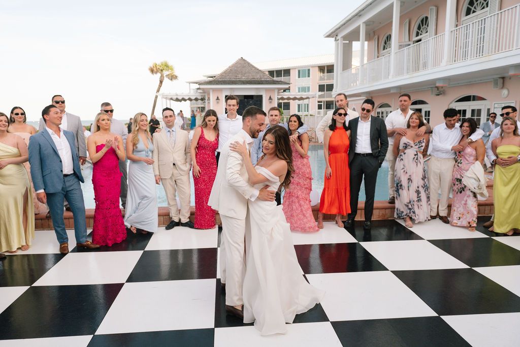 Guests enjoy dancing on a black and white checkered dance floor at an outdoor wedding reception.