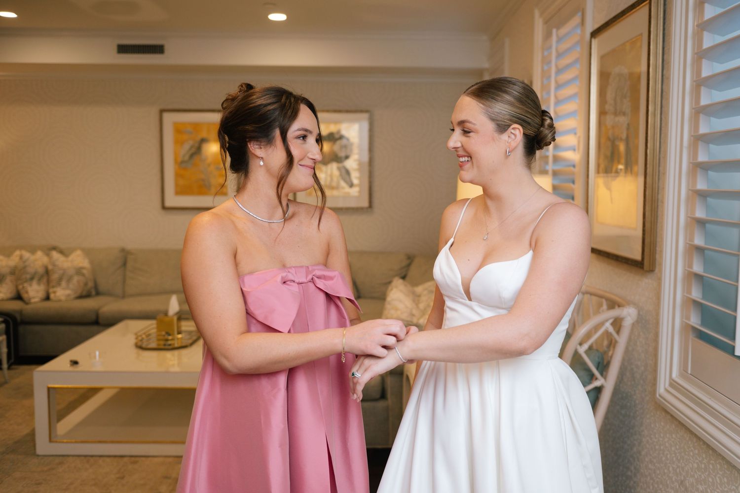 Two women in formal attire sharing an emotional moment in an elegant indoor setting.