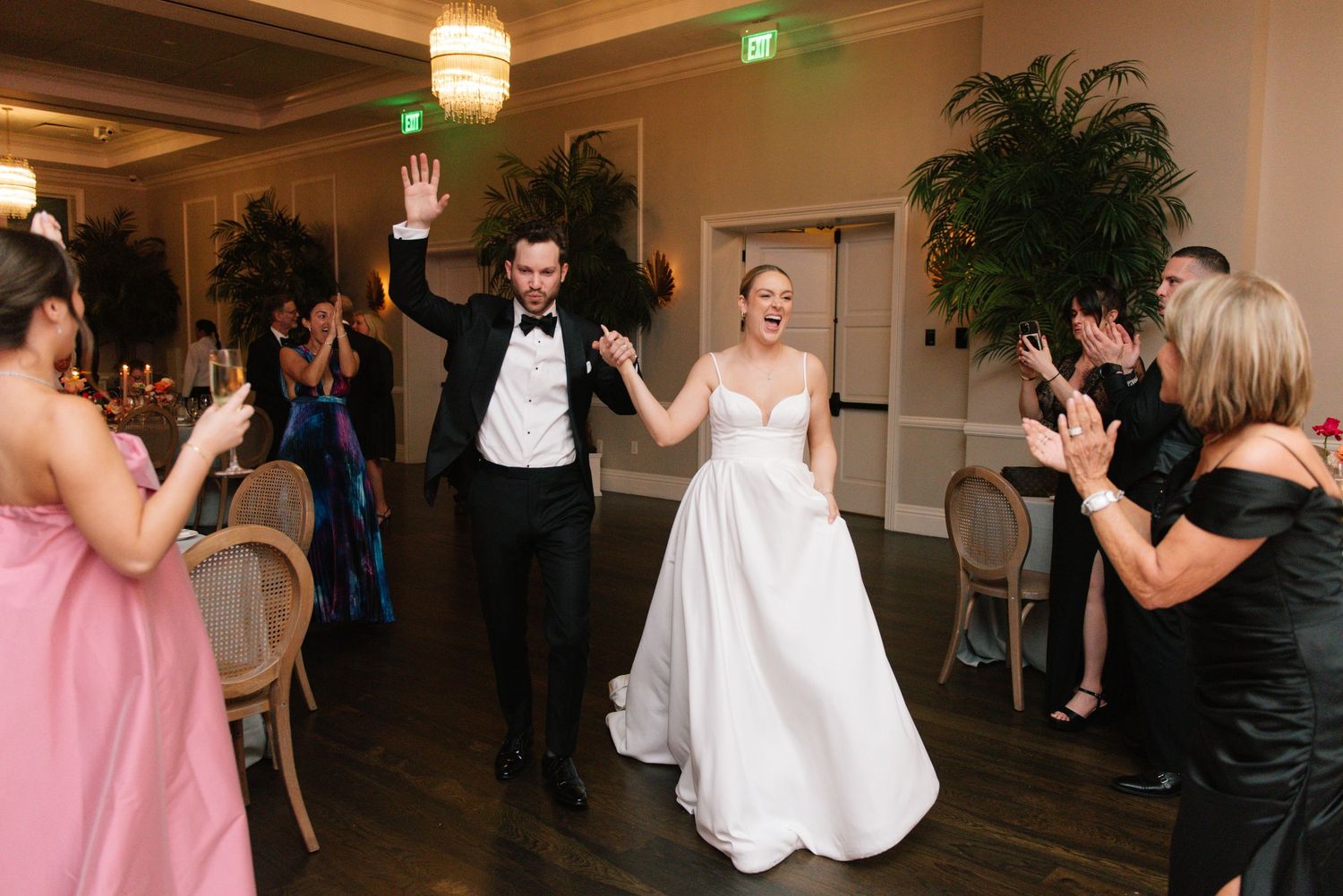 Wedding guests dancing and celebrating on a dimly lit dance floor.
