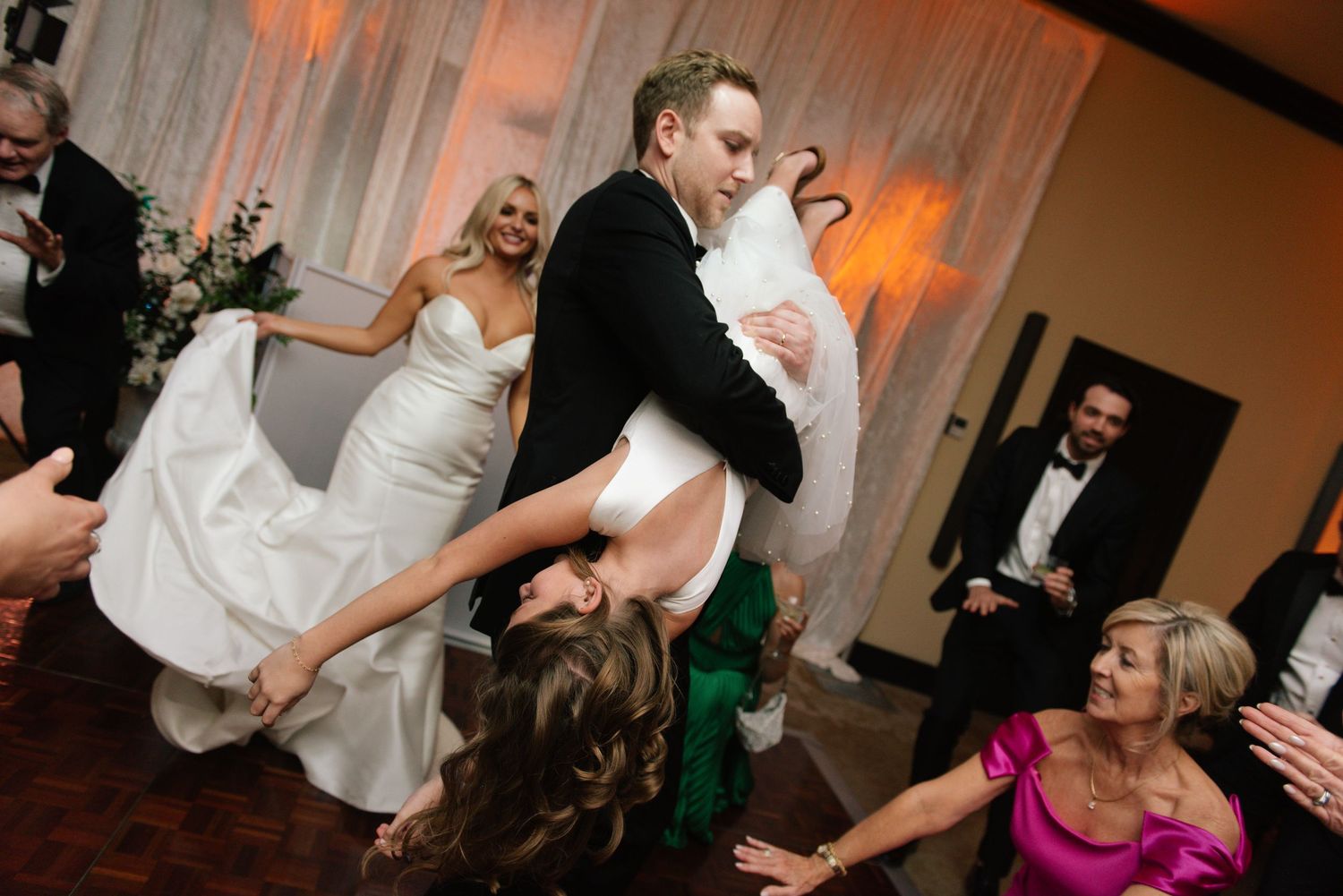 Lively dance floor celebration at a wedding reception with guests in formal attire.