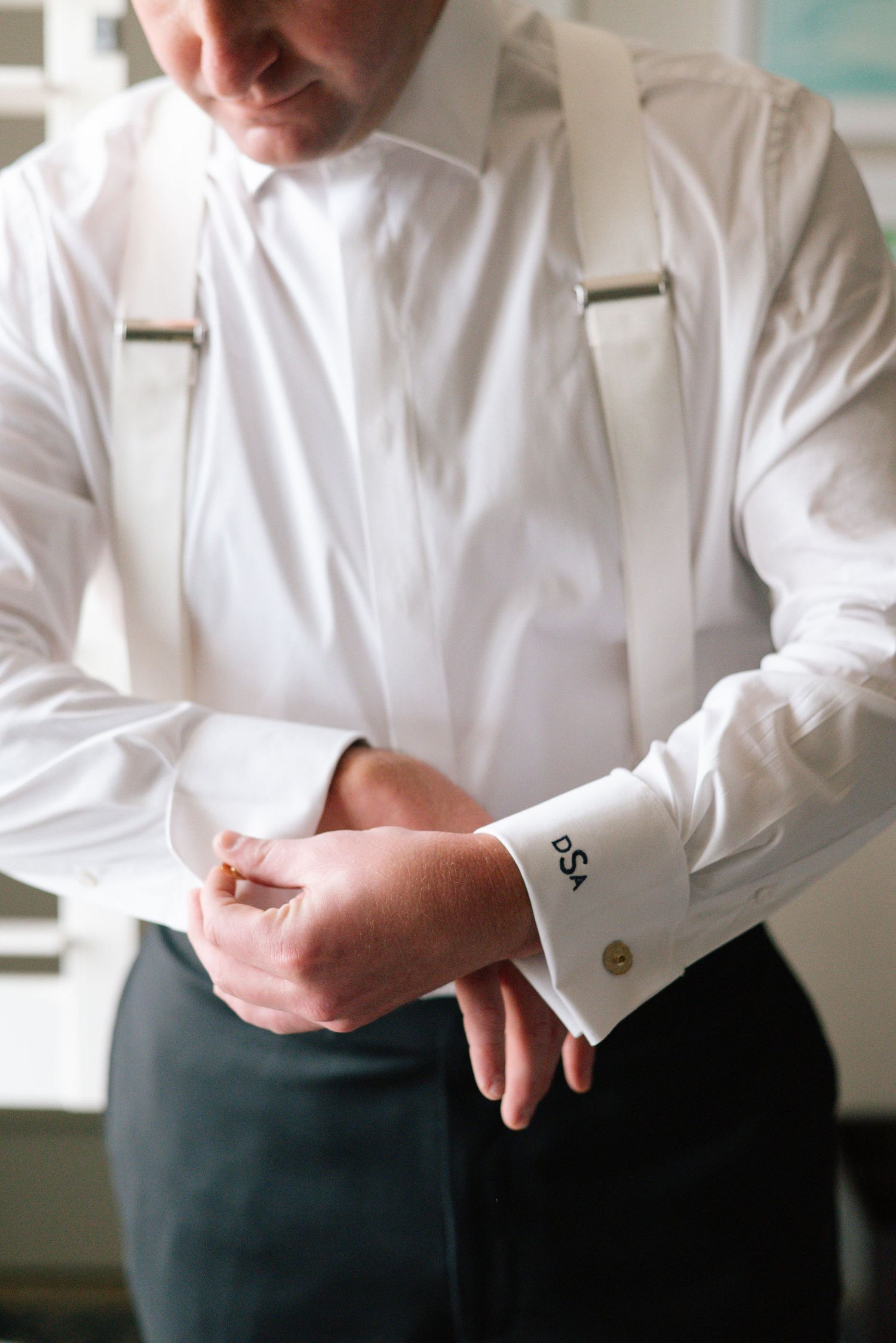 Close-up of formal white dress shirt with cufflinks being adjusted.