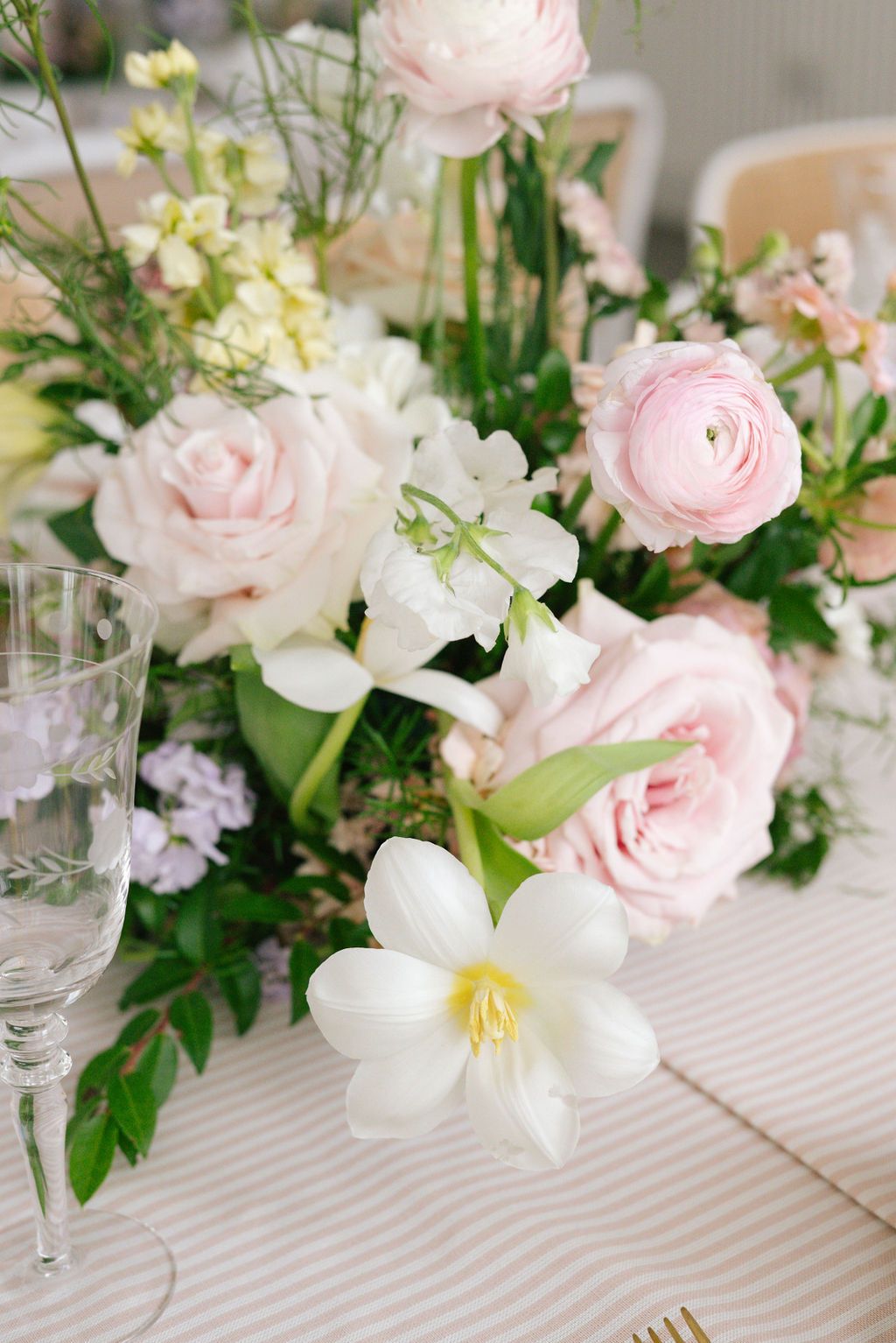 Close-up of pink and white garden roses with lilies in a romantic table arrangement.