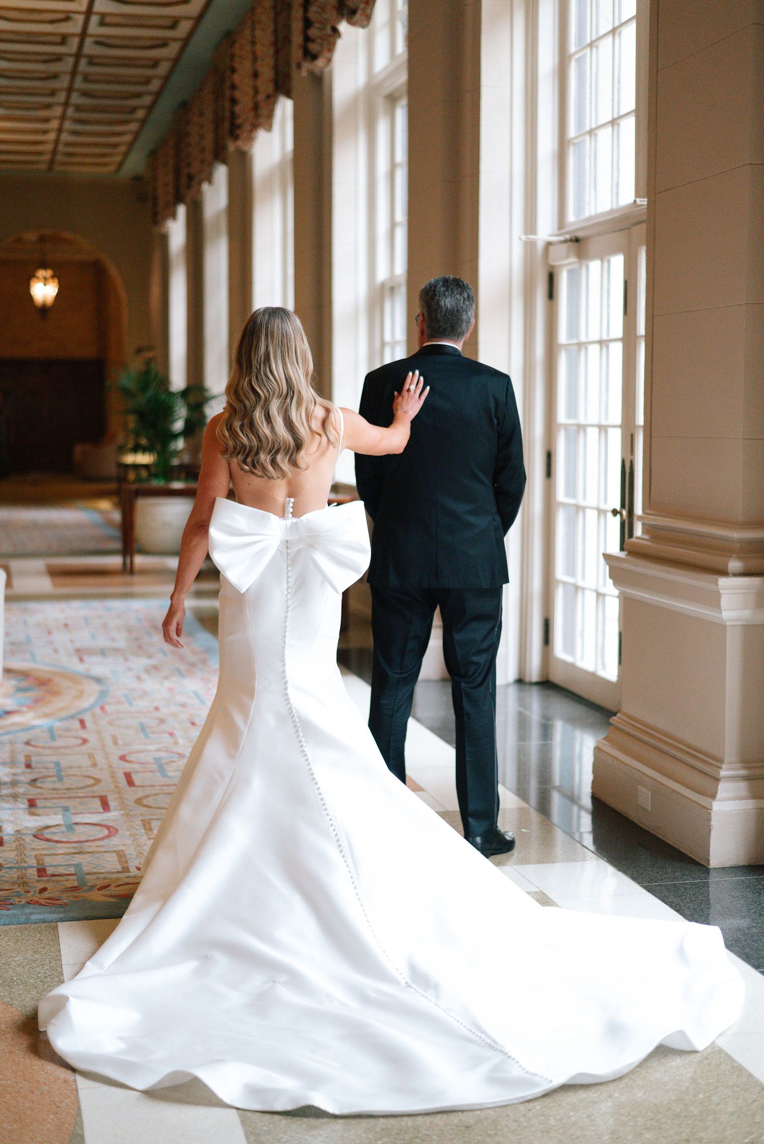 Elegant white wedding dress with dramatic train photographed in sequence along a sunlit hallway.